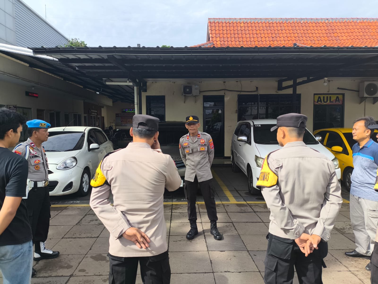 Seorang petugas polisi berbicara kepada anggota lainnya di area parkir.
