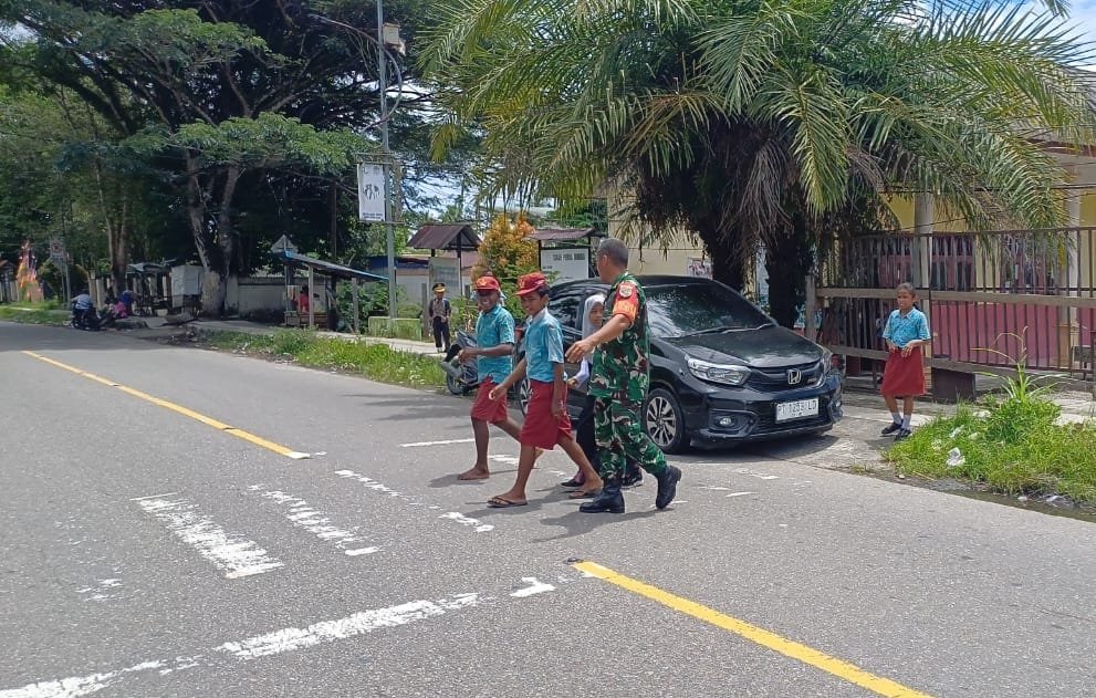 Peduli Keselamatan Anak Sekolah, Secara Rutin Babinsa Koramil Jajaran Kodim 1710/Mimika Bantu Seberangkan Jalan